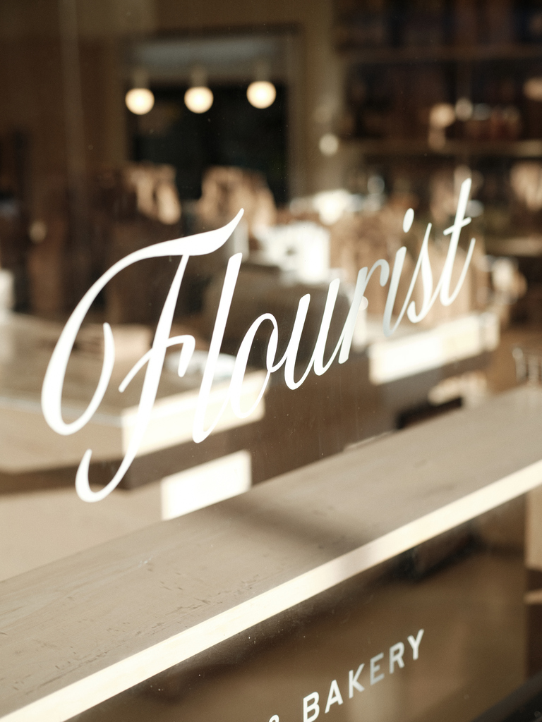 Flourist bakery window sign with blurred interior, showcasing artisanal bread atmosphere.