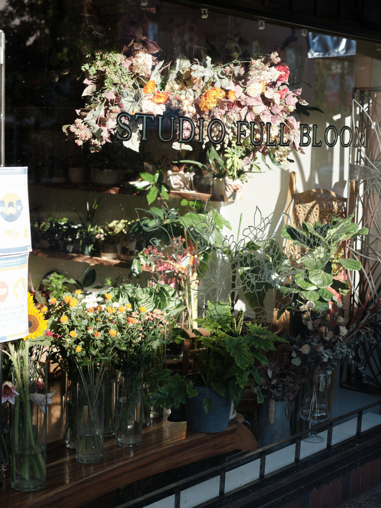 Flower shop window display with vibrant floral arrangements and Studio Full Bloom sign.